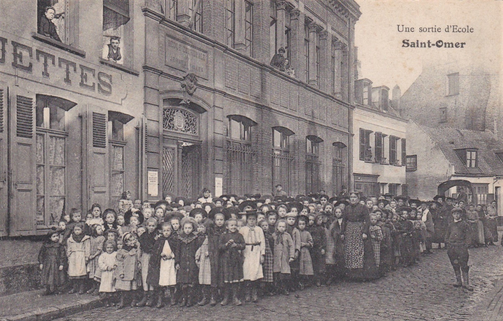 On voit ici une école communale, toutes les élèves sont sorties pour la photo. Sur la gauche de l'école il y avait une fabrique de casquettes.
